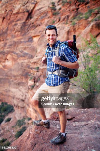 portrait of confident male hiker standing against mountain - confidence male landscape stock-fotos und bilder