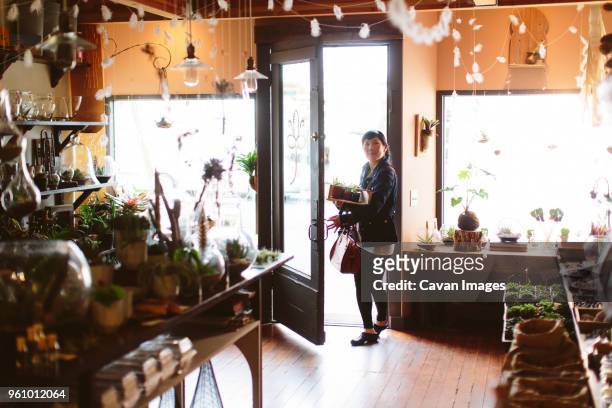 customer carrying crate of plants entering into garden center - entering shop stock pictures, royalty-free photos & images