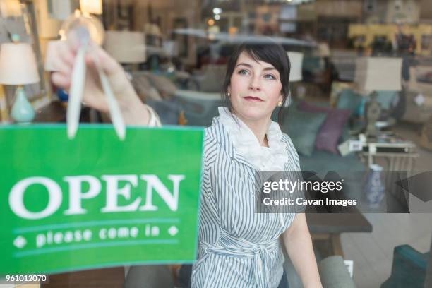 woman hanging open sign on window in furniture store - bordje-met-openingstijden stockfoto's en -beelden