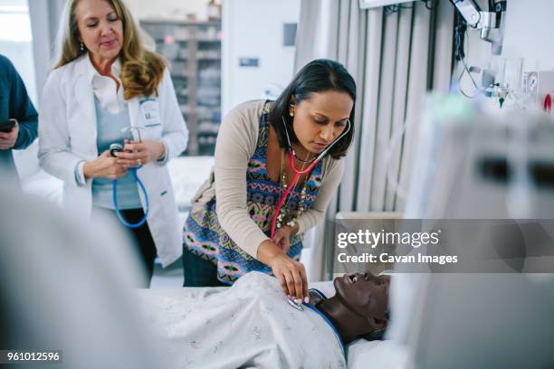female doctor training coworkers while examining mannequin in medical school - medical school stock pictures, royalty-free photos & images