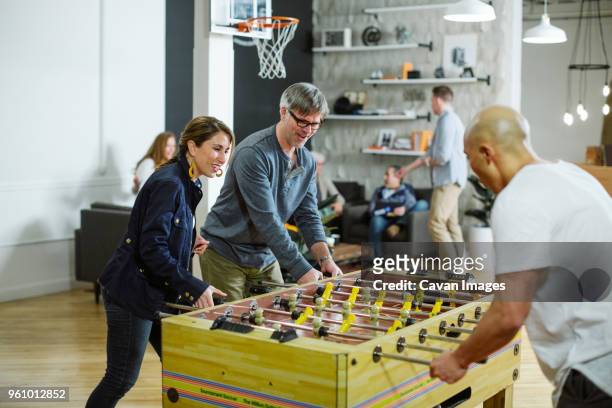 business people playing foosball in office - office fun stock pictures, royalty-free photos & images