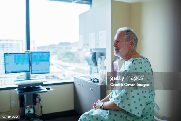 patient looking away while relaxing on bed in hospital ward - sick window stock-fotos und bilder