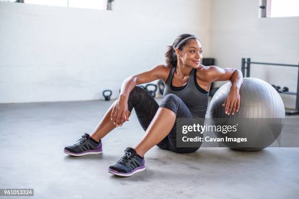smiling athlete looking away while exercising with medicine ball in gym - medicine ball stock pictures, royalty-free photos & images