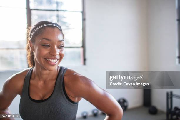 close-up of smiling athlete looking away while standing in gym - ropa de deporte fotografías e imágenes de stock
