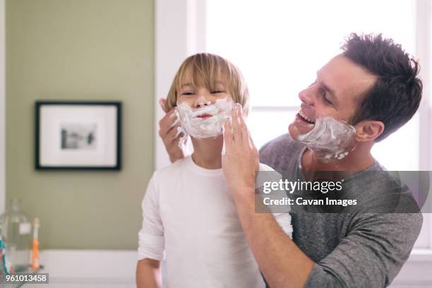 father applying shaving cream to son in bathroom - shaving cream stock pictures, royalty-free photos & images