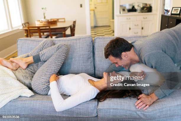 happy couple in living room at home - auf dem bauch liegen stock-fotos und bilder