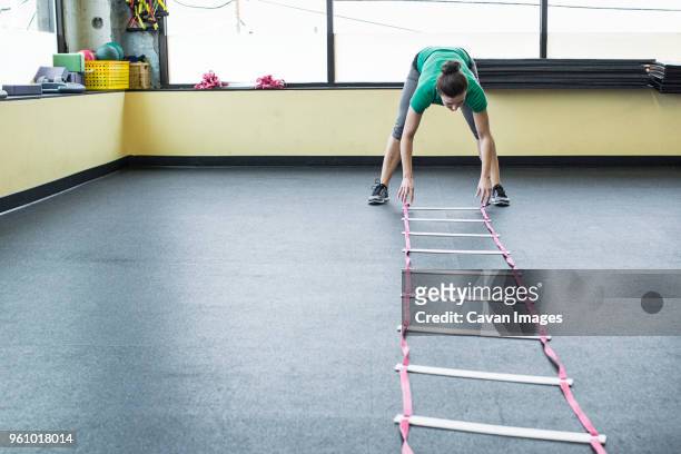 instructor placing agility ladder on floor in gym - agility ladder stock pictures, royalty-free photos & images