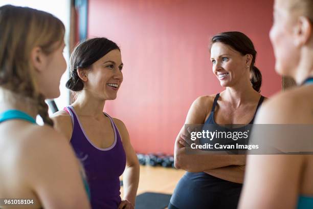 happy female friends talking while standing in health club - four people foto e immagini stock