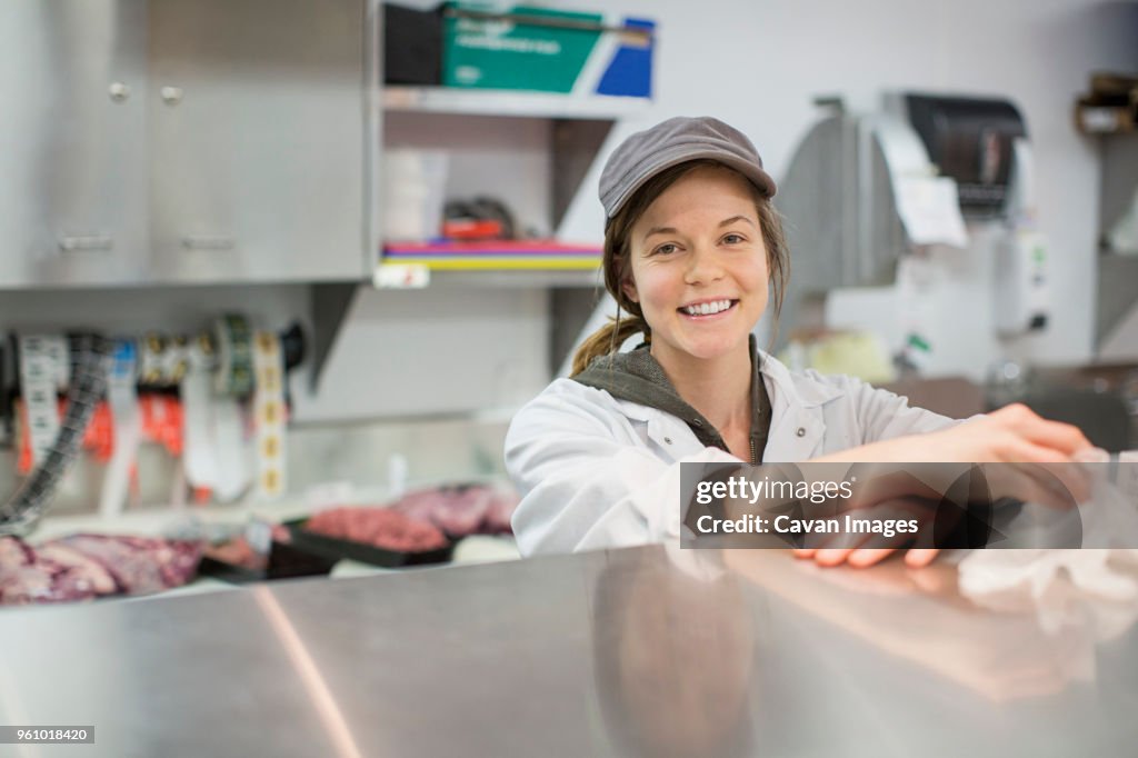 Portrait of happy female worker standing by display cabinet