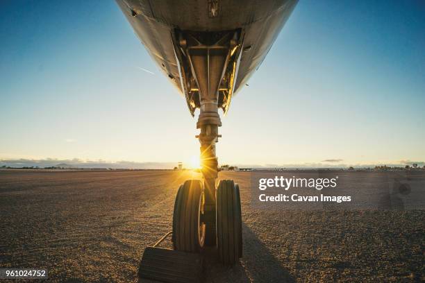 cropped airplane at runway against sky during sunset - landing gear - fotografias e filmes do acervo