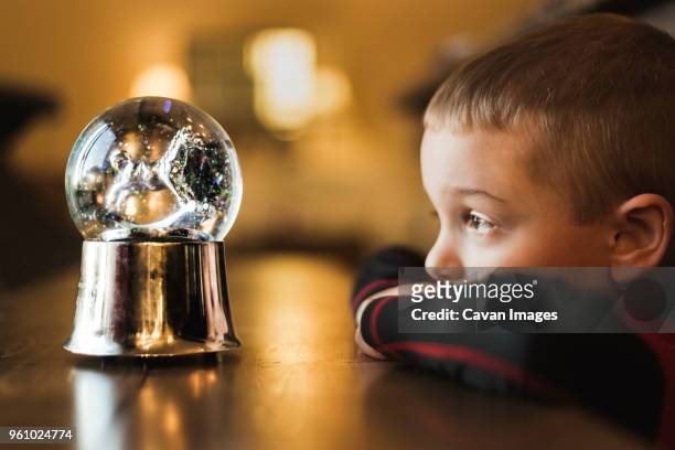 side view of boy looking at snow globe - snow globe stock-fotos und bilder