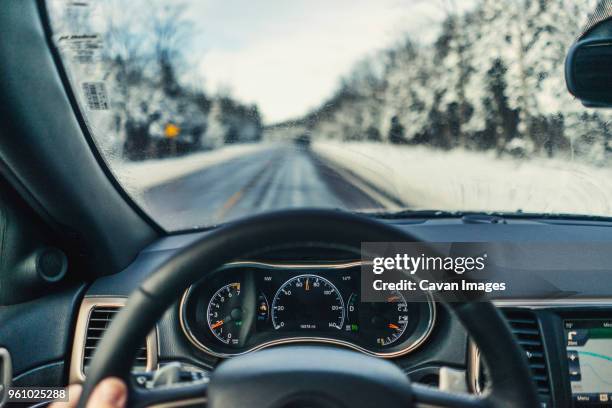 cropped fingers of man driving car on road during winter - cuadro de instrumentos fotografías e imágenes de stock