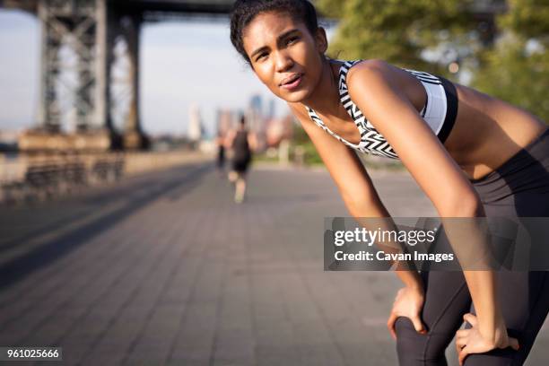 tired jogger resting on footpath - hand op knie stockfoto's en -beelden