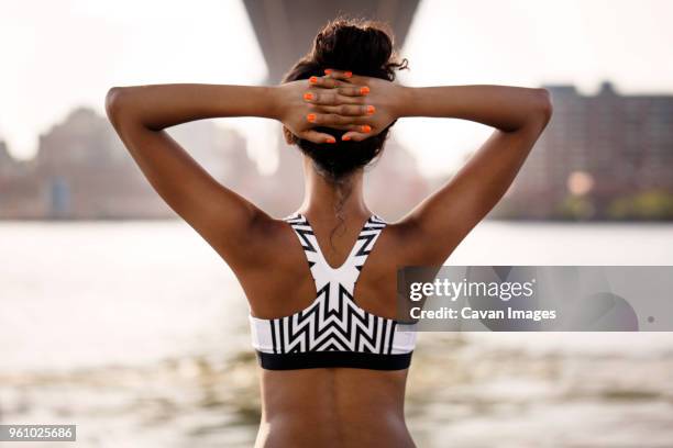 rear view of female jogger with hands behind head - stretching hands behind head rear view stock-fotos und bilder