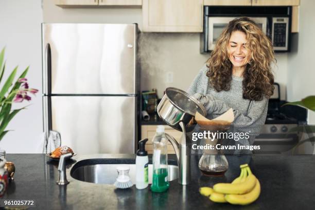 happy woman pouring coffee in filter at kitchen counter - refrigerator front stock pictures, royalty-free photos & images