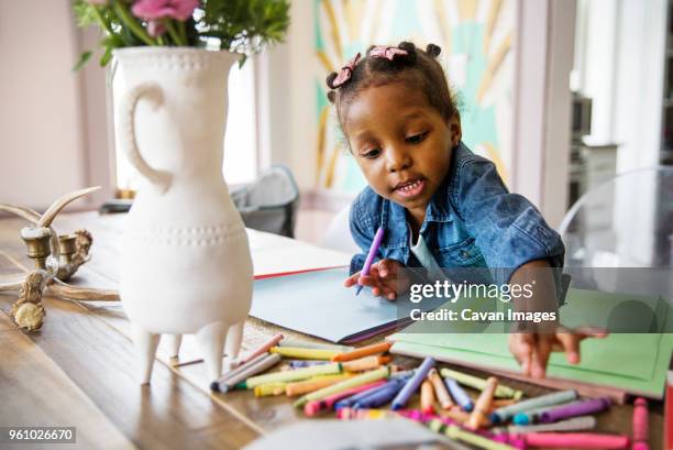 cute girl reaching for colored crayons on table at home - crayon stock pictures, royalty-free photos & images