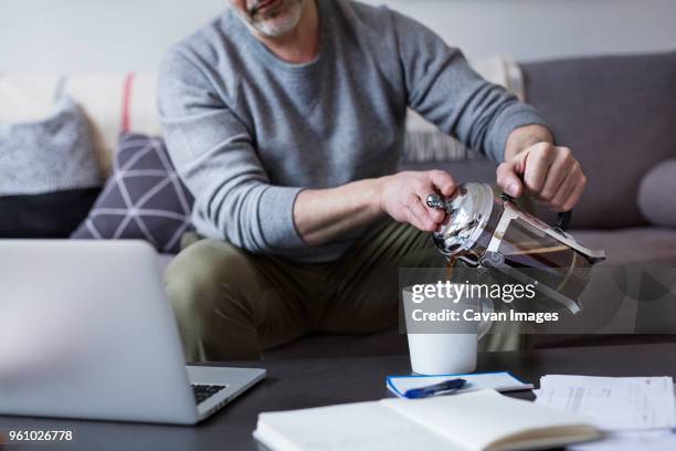 midsection of man pouring coffee from french press in mug at home - coffee plunger stock pictures, royalty-free photos & images