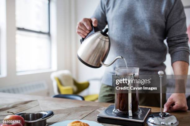 midsection of man pouring water in french press while preparing coffee at home - coffee machine home stock pictures, royalty-free photos & images