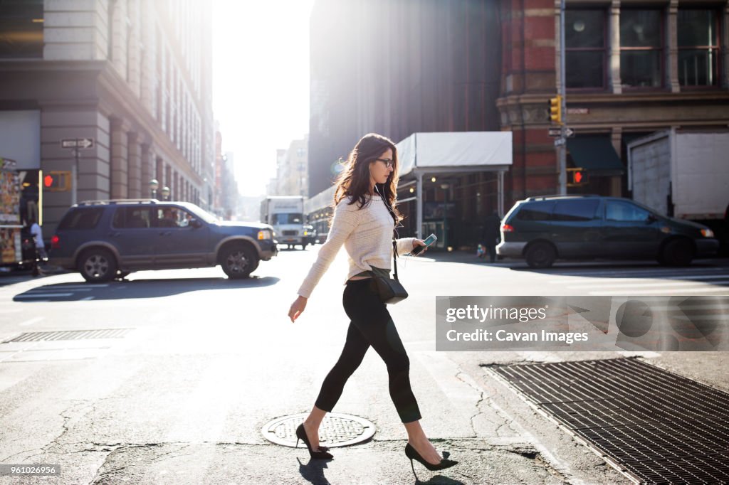 Full length of young woman walking on city street