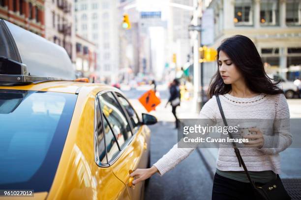 young woman opening door of taxi on city street - coffee car design stock pictures, royalty-free photos & images