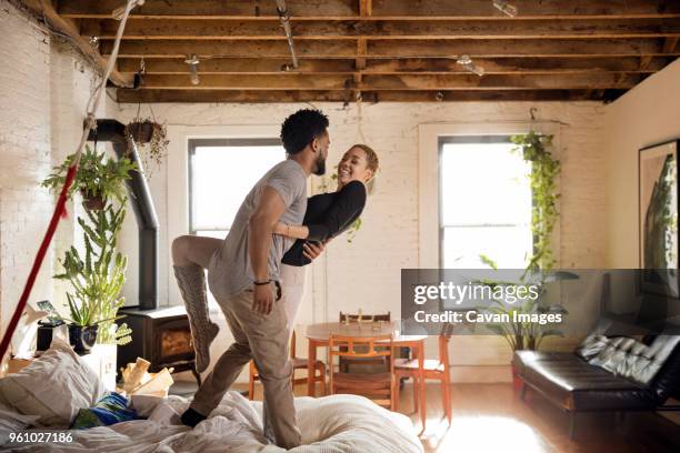 cheerful multi-ethnic couple dancing on bed at home - couple dancing at home stockfoto's en -beelden