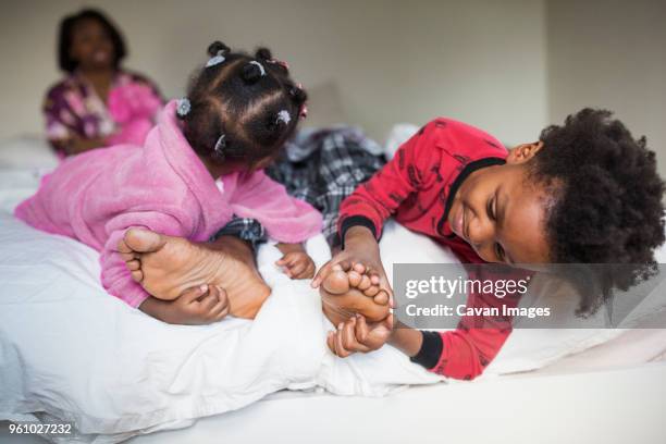 children tickling fathers feet on bed - kietelen stockfoto's en -beelden