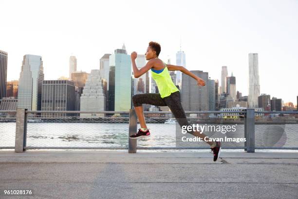 athlete jumping on promenade by river against clear sky - one world trade center 個照片及圖片檔