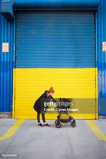 side view of woman with baby carriage on street - baby blue stock pictures, royalty-free photos & images