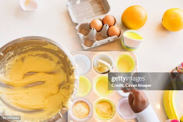 cropped image of girl filling batter in cupcake holder - cupcake holder stock pictures, royalty-free photos & images