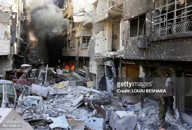 Syrian government forces walk down a destroyed street in the Hajar al-Aswad area on the southern outskirts of Damascus on May 21 after the Syrian...