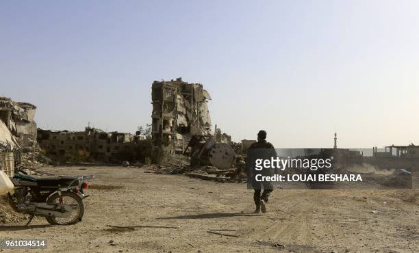 Member of the Syrian government forces walks down a destroyed street in the Hajar al-Aswad area on the southern outskirts of Damascus on May 21 after...