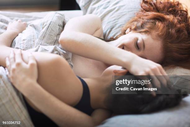 high angle view of lesbian couple romancing on bed at home - lesbian bed stock pictures, royalty-free photos & images