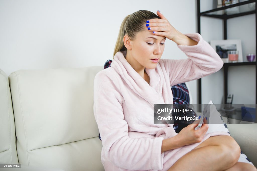 Sick woman watching the thermometer she worries about health