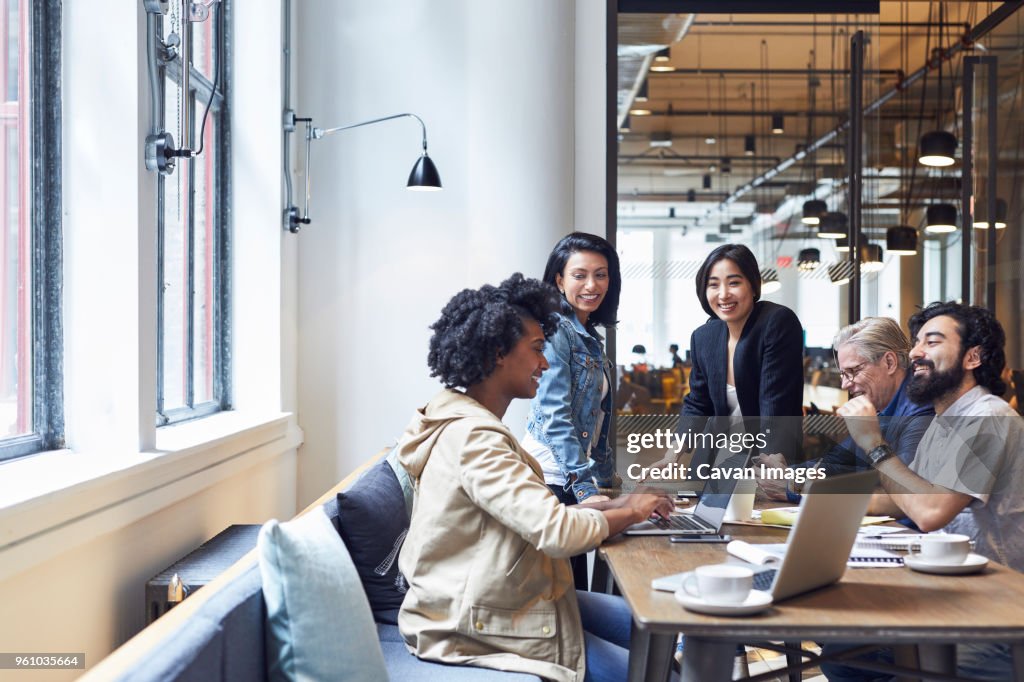 Happy business people having discussion during meeting in office