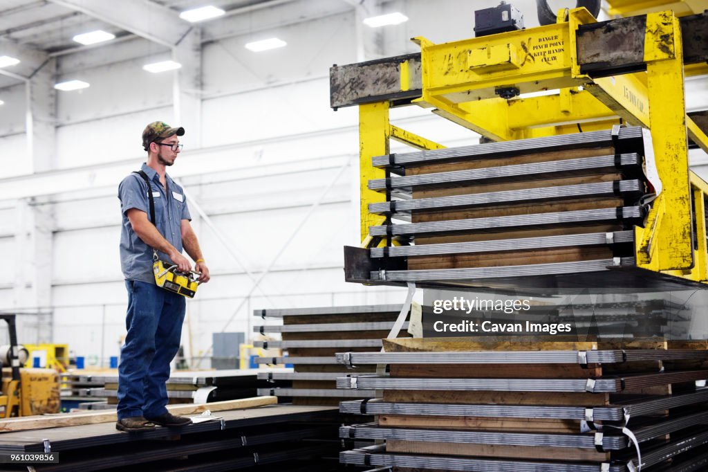 Worker operating overhead crane in metal Steel Mill