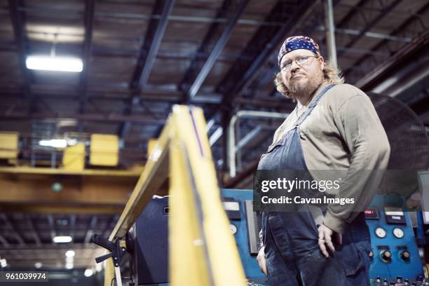 low angle view of blue collar worker wearing bib overalls and headscarf while working in steel industry - low confidence stock pictures, royalty-free photos & images
