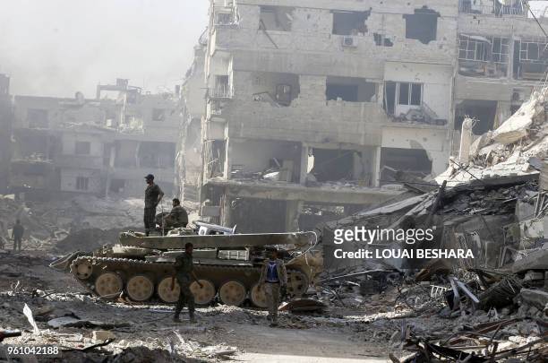 Syrian government forces stand in a destroyed street in the Palestinian camp of Yarmuk on the southern outskirts of Damascus on May 21 after the...