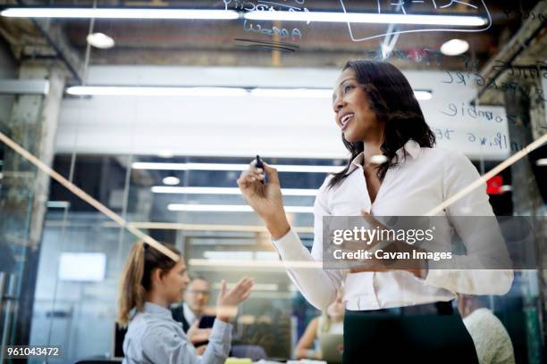 low angle view of businesswoman writing on glass with felt tip pen during meeting at board room - felt board stock pictures, royalty-free photos & images