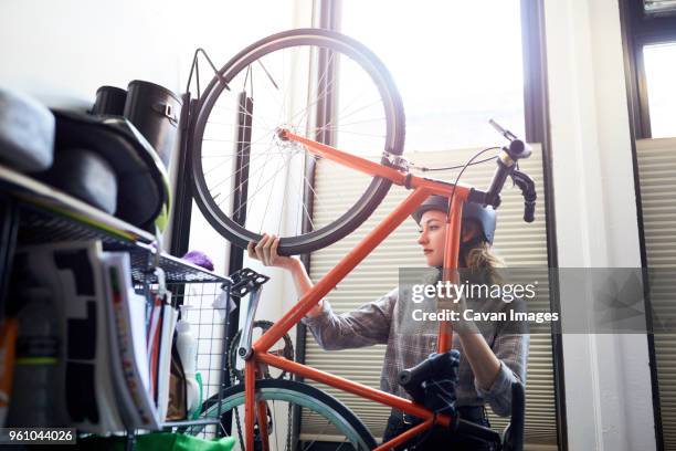 businesswoman removing bicycle from rack in creative office - remove clothes from stock-fotos und bilder