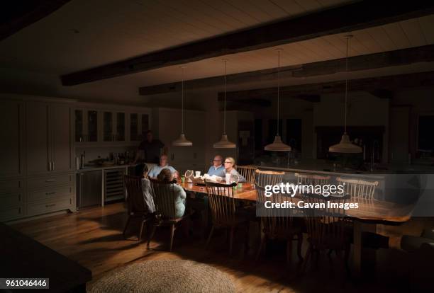 family sitting at illuminated dining table - father and son discussion stock-fotos und bilder