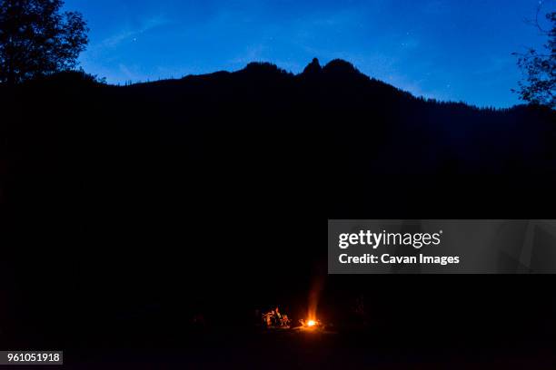 hiker camping against silhouette mountains during night - distant fire stock pictures, royalty-free photos & images
