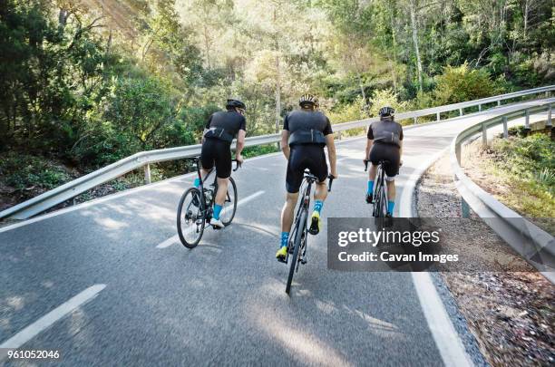 rear view of male friends cycling on road - cycling bicycle sports race stock pictures, royalty-free photos & images