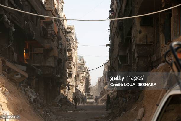 Syrian government forces walk down a destroyed street in the Palestinian camp of Yarmuk on the southern outskirts of Damascus on May 21 after the...