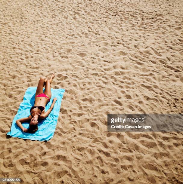 high angle view of woman sunbathing on beach - telo da mare foto e immagini stock