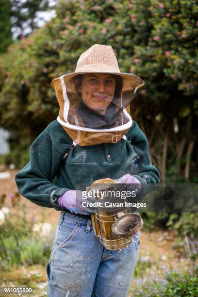 portrait of female beekeeper wearing protective workwear while standing at farm - apiculture stock pictures, royalty-free photos & images