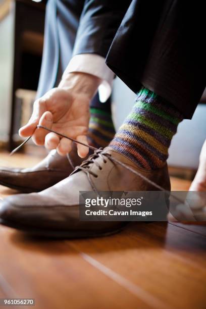 low section of bridegroom tying shoelace at home - zapatos marrones fotografías e imágenes de stock
