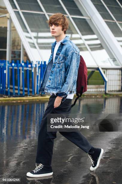Model Lennon Gallagher wears a denim jacket, red backpack, black pants, and black sneakers during Paris Fashion Week Menswear Fall/Winter 2018 on...