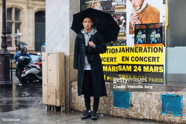 Chinese model Zhang Wenhui carries a black umbrella and wears a long black coat, gray hoodie, black pants, and black Nike Air Max sneakers during...