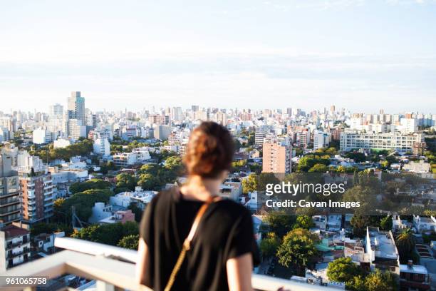 rear view of woman standing at building terrace against cityscape - buenos aires people stock-fotos und bilder