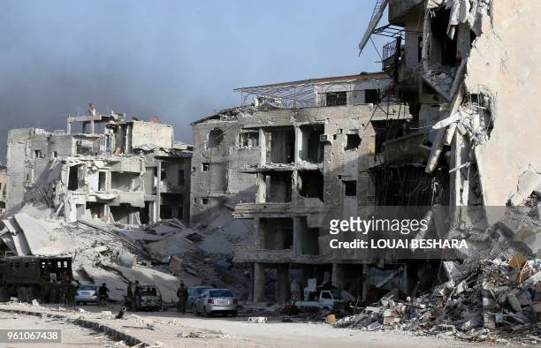 Syrian government forces stand on a destroyed street in the Hajar al-Aswad area on the southern outskirts of Damascus on May 21 after the Syrian army...